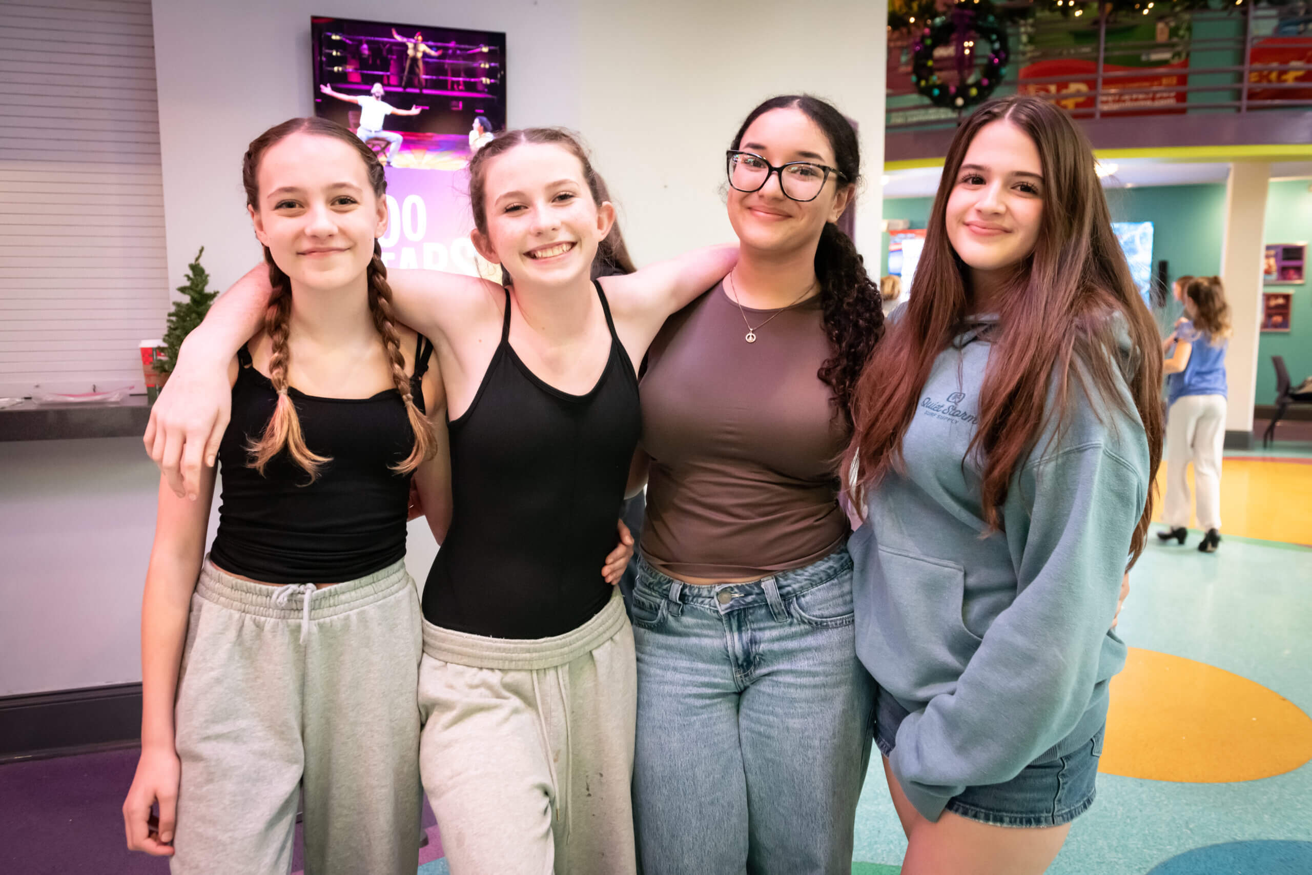 Four teen performers in warm-up attire smile to the camera
